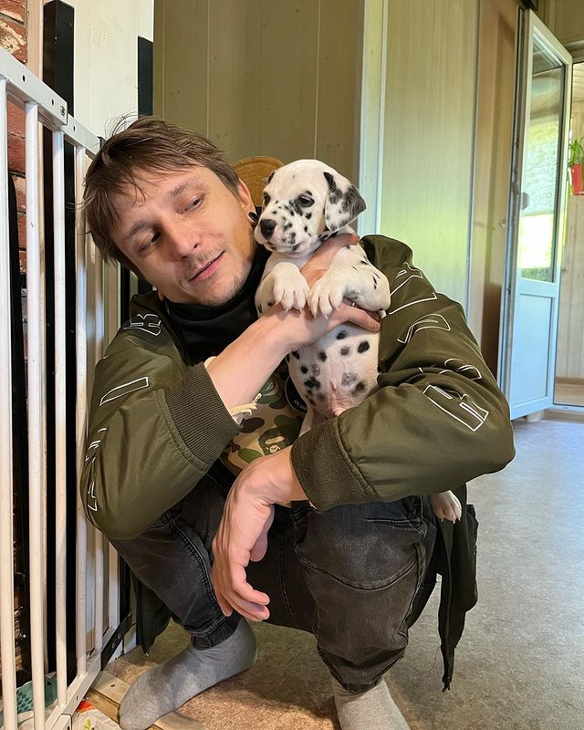 uglyfate sentado de cuclillas sosteniendo un hermoso cachorro de dalmata en sus brazos